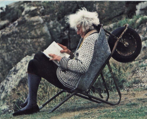 This may contain: an old woman sitting in a chair reading a book with the words read books enjoy life stay awesome