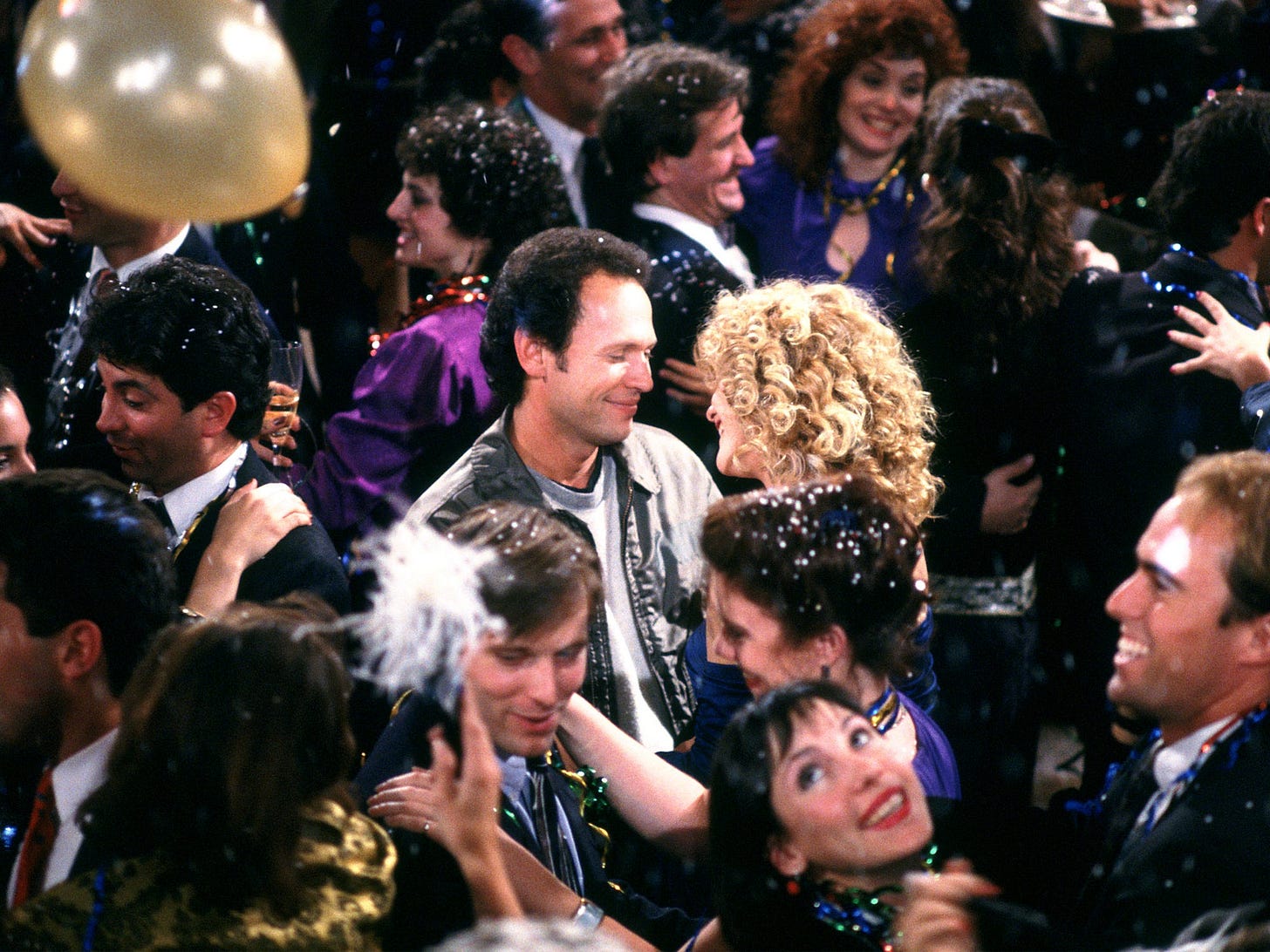 Screen grab from the film 'When Harry Met Sally' of the two titular characters smiling at each other in the middle of a New Year's party.