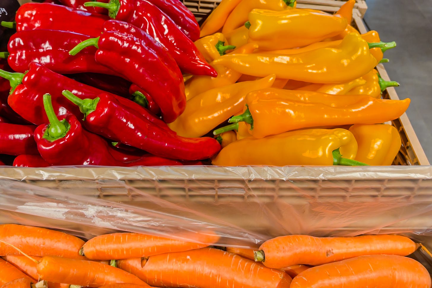 Kisten mit frischem Gemüse auf einem Marktstand: oben links leuchtend rote Spitzpaprika, daneben gelbe Paprika, darunter orangefarbene Karotten. Die kräftigen Farben des Gemüses bilden einen harmonischen, warmen Kontrast. Kisten mit frischem Gemüse auf einem Marktstand: oben links leuchtend rote Spitzpaprika, daneben gelbe Paprika, darunter orangefarbene Karotten. Die kräftigen Farben des Gemüses bilden einen harmonischen, warmen Kontrast.