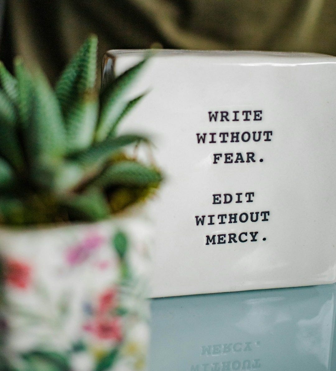 a white box with writing on it next to a plant