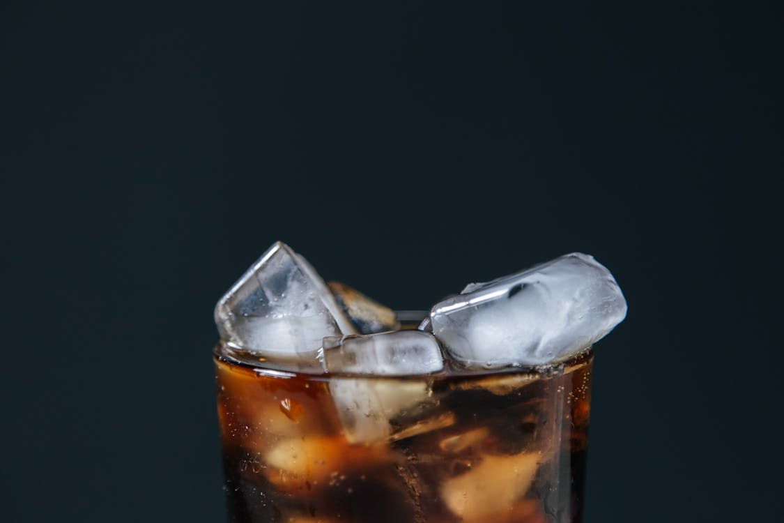 Free Extreme close-up of a fizzy cola drink with ice cubes, perfect for a refreshing treat. Stock Photo