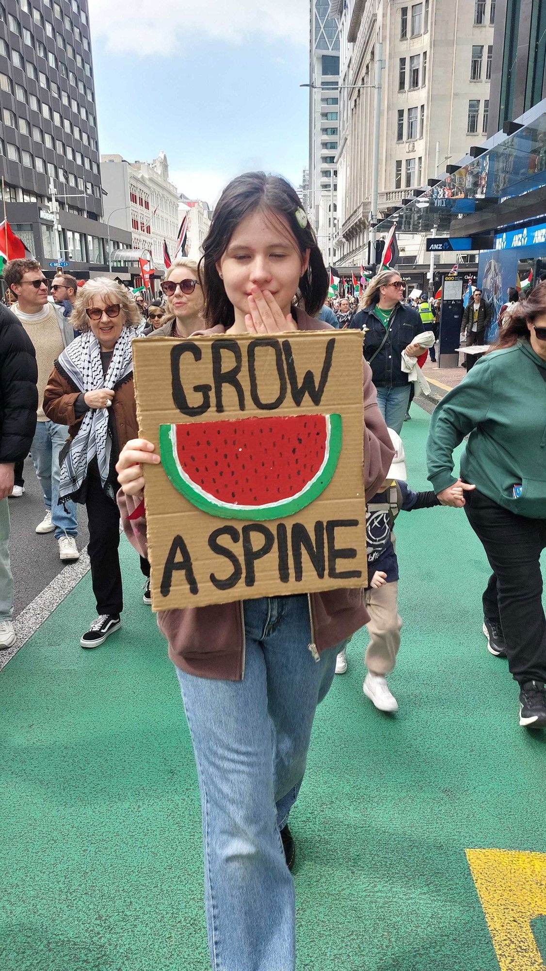 Protestor with a sign that reads "Grow a spine."