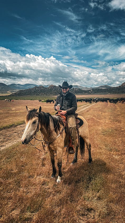 A man on horse back wearing a Filson tin cruiser and a black cowboy hat in the Utah desert with mountains and storm clouds in the background.