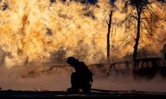 A firefighter kneeling in front of a fire
AI-generated content may be incorrect.