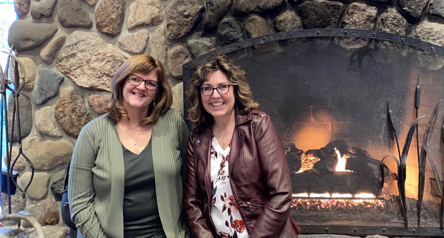 Two writer-friends in front of big stone fireplace.