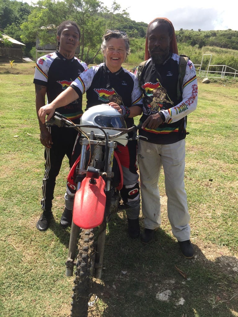 Three people standing around a trail bike