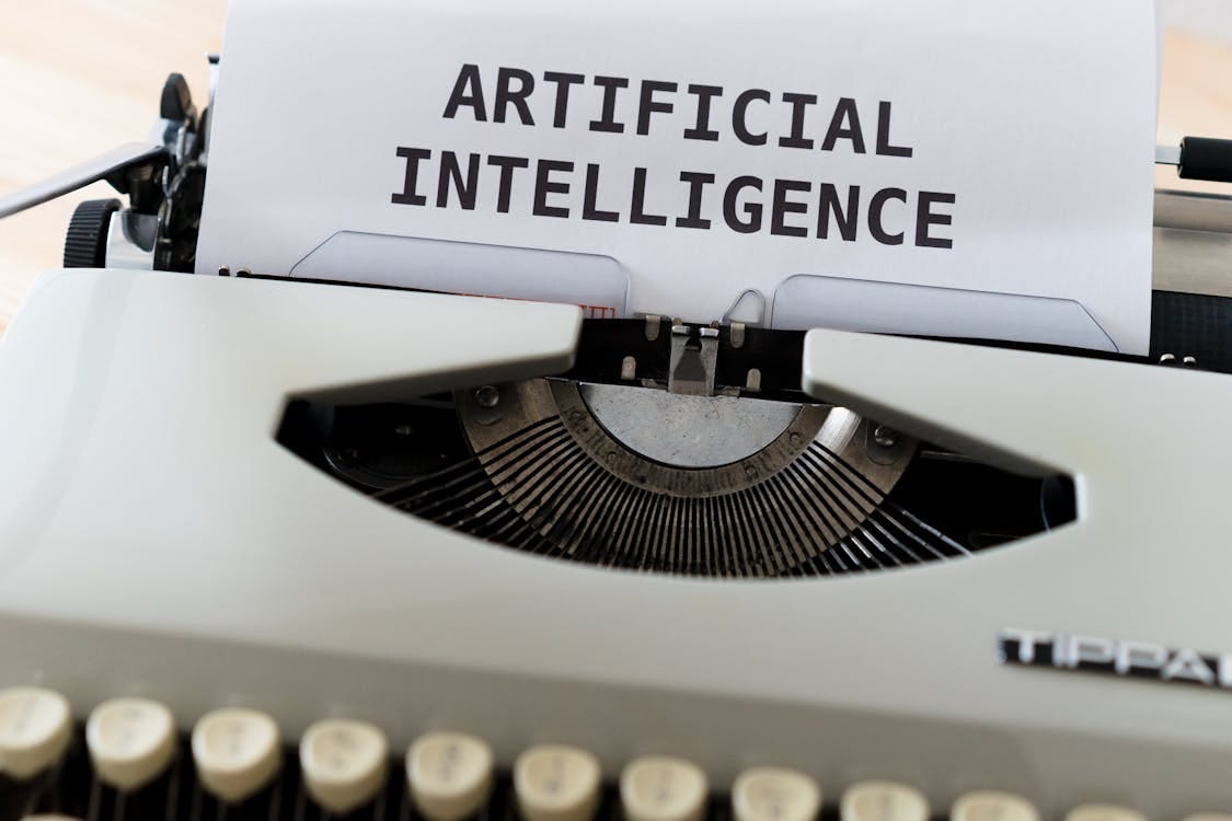 Free A close-up of a typewriter showcasing 'ARTIFICIAL INTELLIGENCE' on paper. Stock Photo