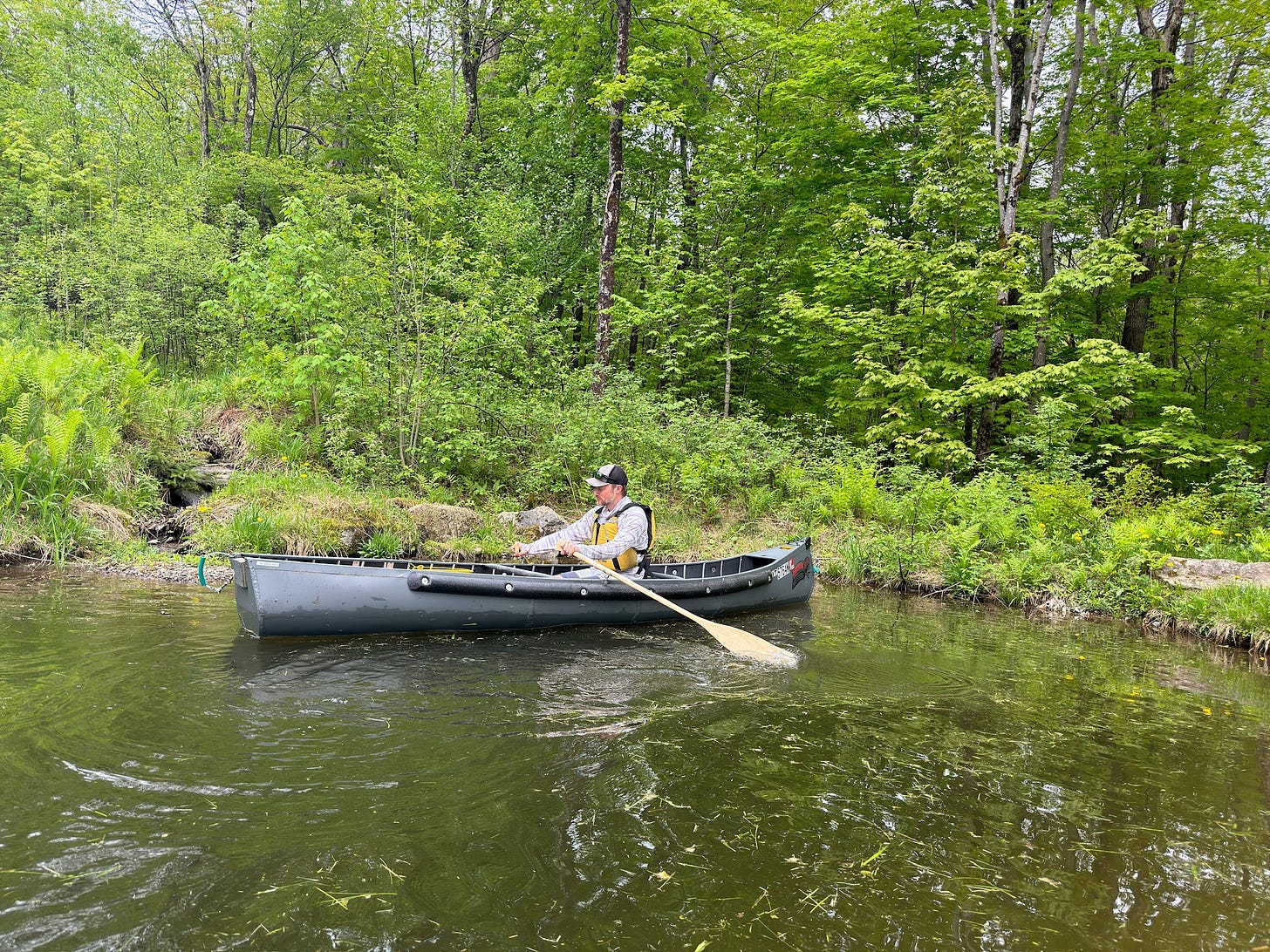 Jesse McEntee using the oar locks of the Radisson canoe on a pond to row the canoe.
