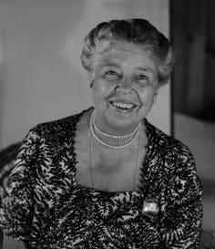 This may contain: an old photo of a woman with pearls on her necklace and smiling at the camera