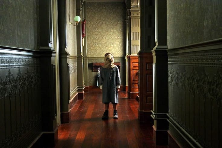 This may contain: a woman walking down a dark hallway in an old building