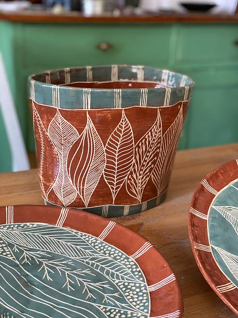 ceramic pieces decorated with a nature abstract design using slips and sgraffito: two platters, two flat panels and a vase