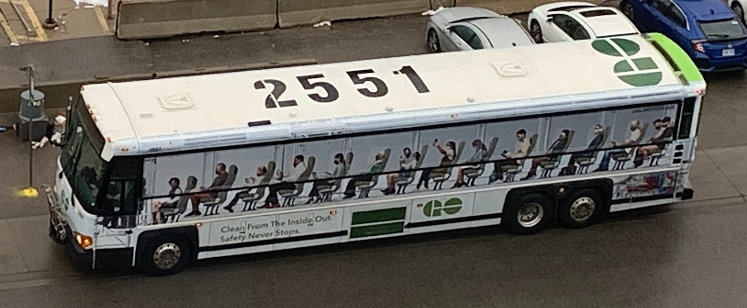 A Metrolinx GO transit bus with a large ad by Metrolinx advertising their bus service, while also blocking the windows.