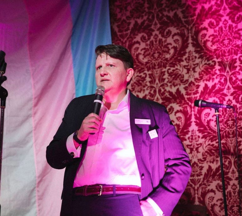 A person in a suit holding a microphone

AI-generated content may be incorrect.