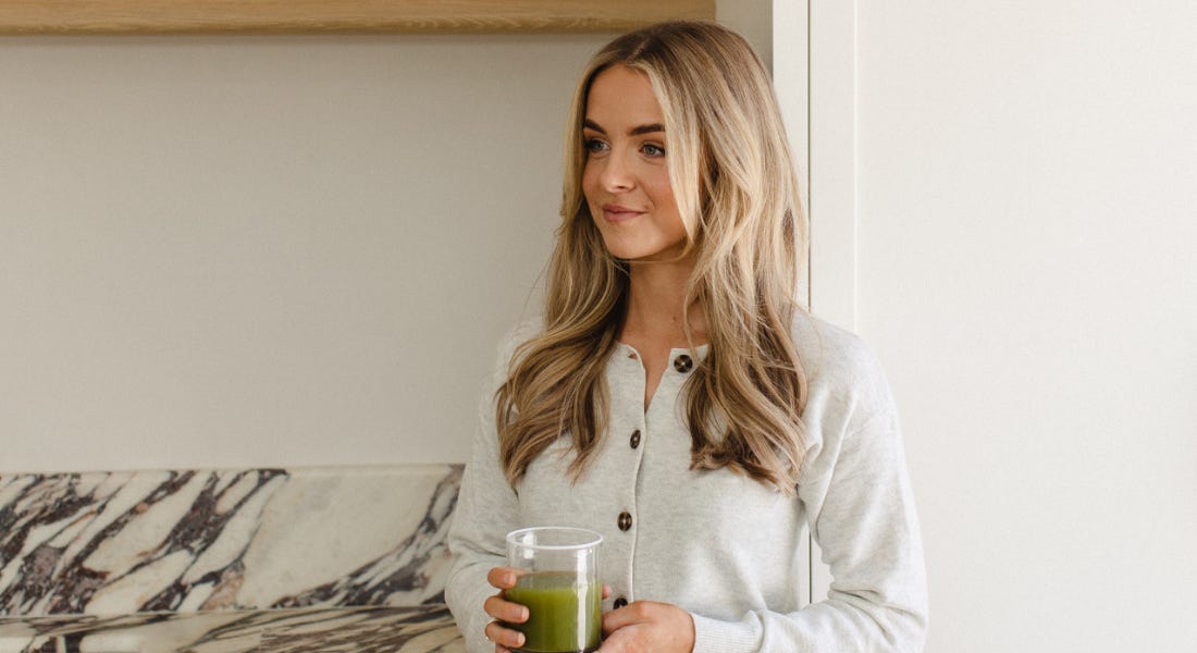A picture of Jessica Ross - a woman with blonde hair holding a green juice, with a marble countertop behind her A picture of Jessica Ross - a woman with blonde hair holding a green juice, with a marble countertop behind her