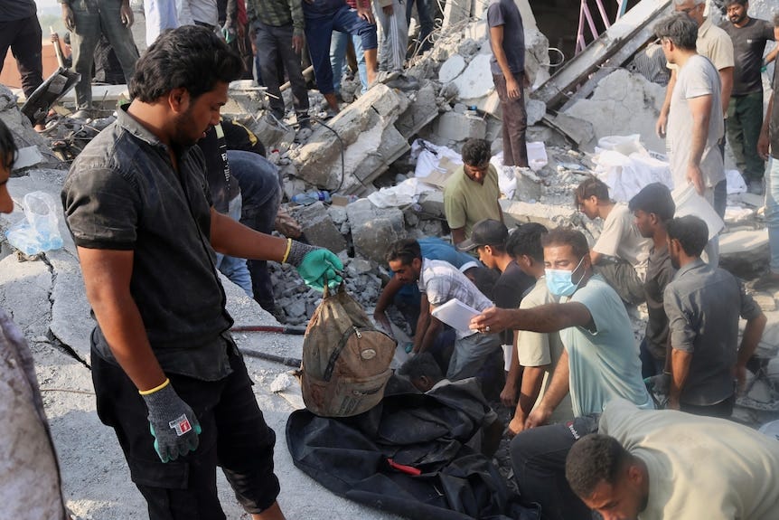 A man hold a children's backpack as rescue workers and residents search through the rubble A man hold a children's backpack as rescue workers and residents search through the rubble