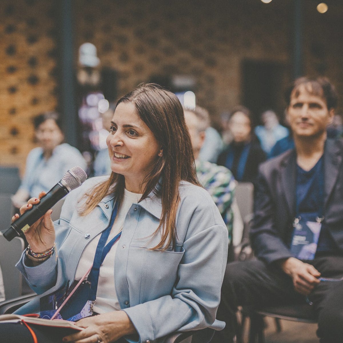Scientist speaking into a microphone during a conference session, smiling while participating in the discussion.