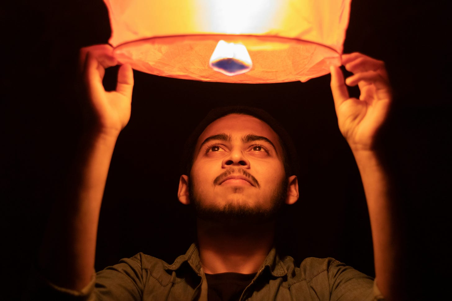 A man releases a lit Chinese lantern