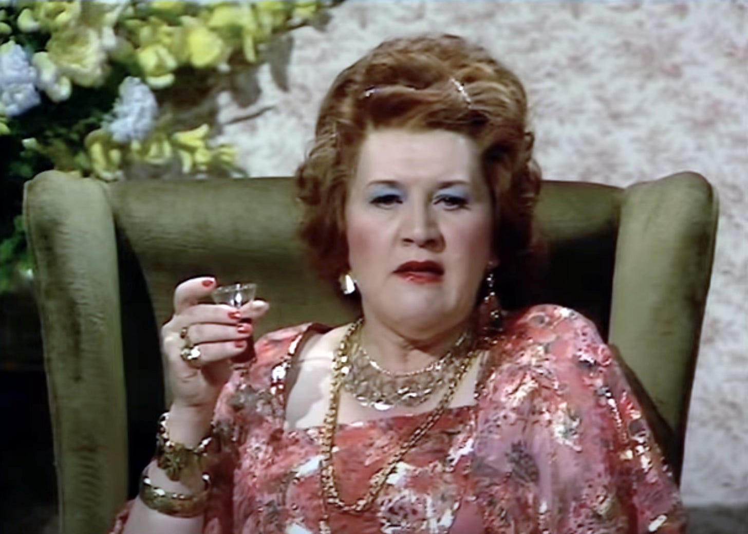 Patricia Routledge as Kitty, sitting in a high-backed chair, holding a sherry
