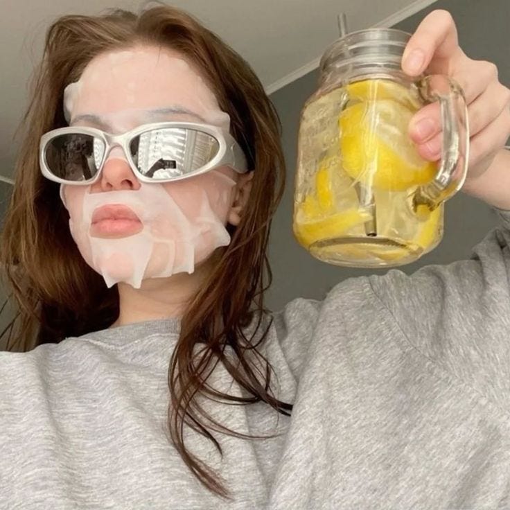 This may contain: a woman wearing sunglasses and holding a jar with lemonade on her face in front of her