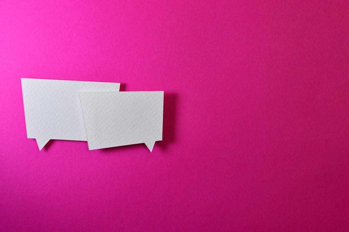 Free White speech bubbles on a vibrant pink background for communication or design concepts. Stock Photo
