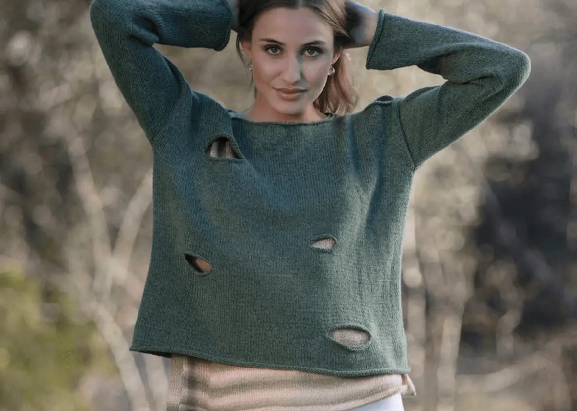 woman wearing dark green sweater with hands on her hair