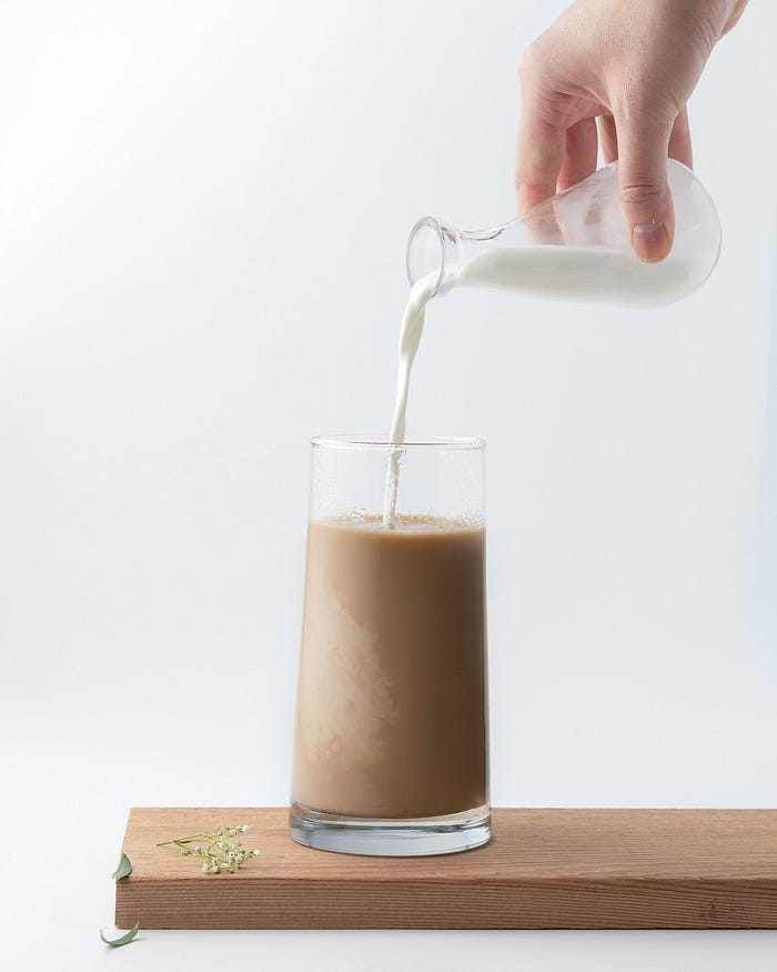 Pouring milk into an iced coffee.