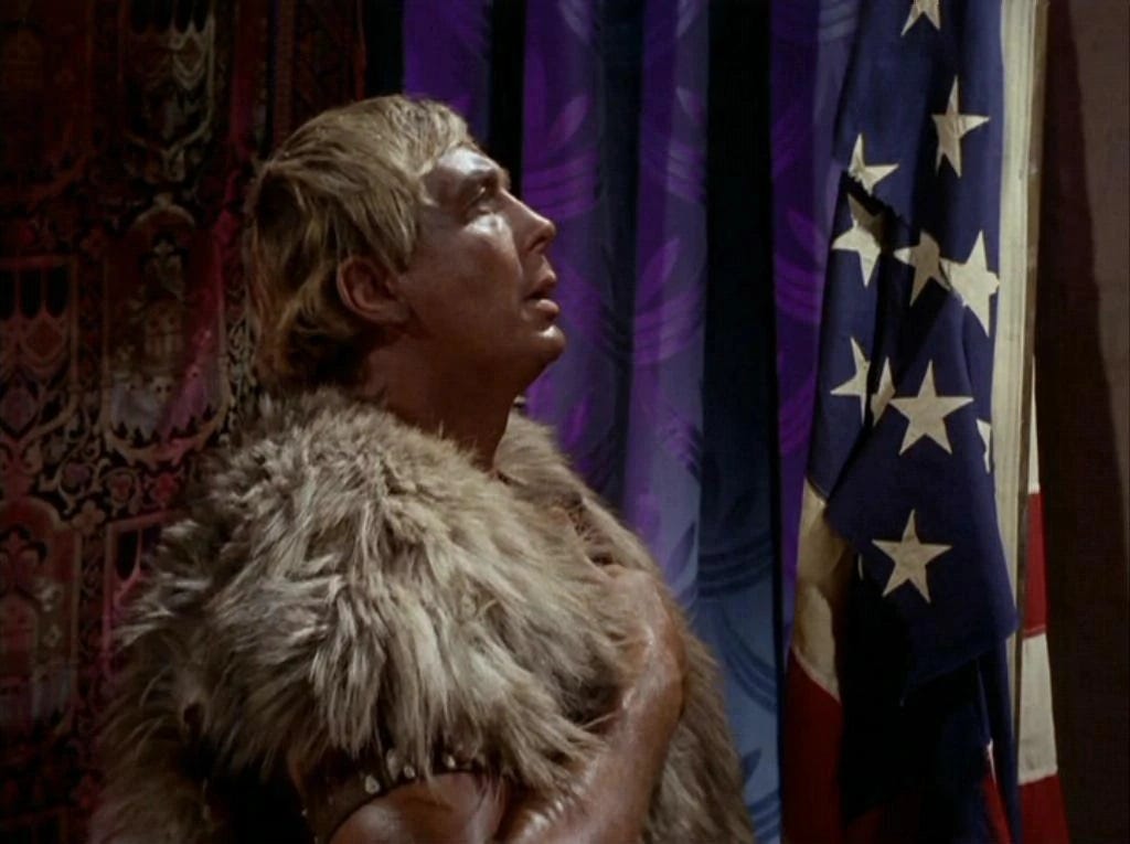 Screenshot from the episode 'Omega Glory' (1968), showing Cloud William, leader of the primitive Yangs, holding his hand over his heart before a tattered US flag. Screenshot from the episode 'Omega Glory' (1968), showing Cloud William, leader of the primitive Yangs, holding his hand over his heart before a tattered US flag.