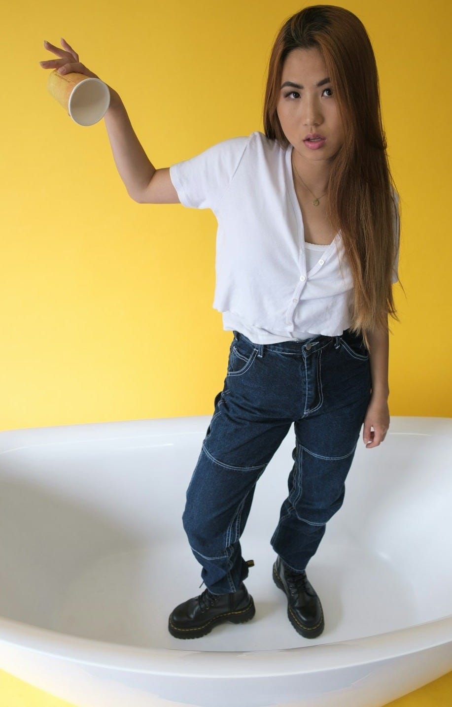 woman in white dress shirt and blue denim jeans standing on bathtub