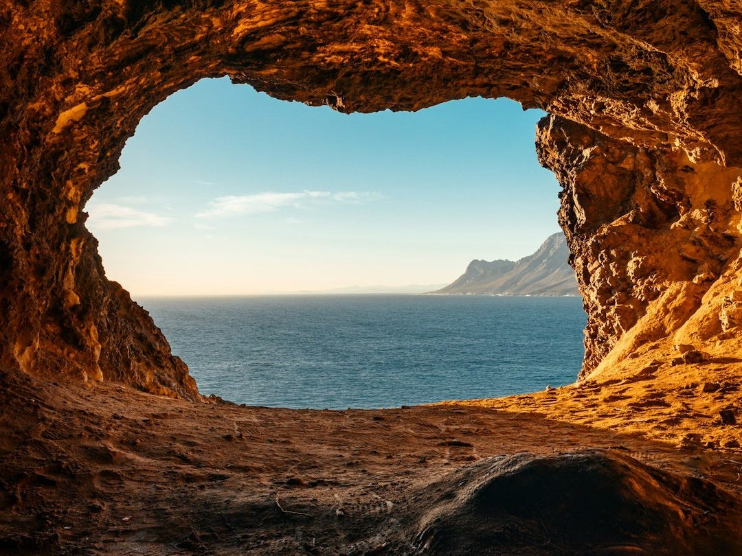 brown cave near body of water during daytime brown cave near body of water during daytime