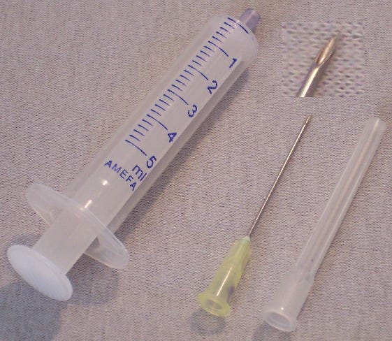 Einweg-Kunststoffspritze und Einweg-Kanüle mit abgezogener Schutzkappe