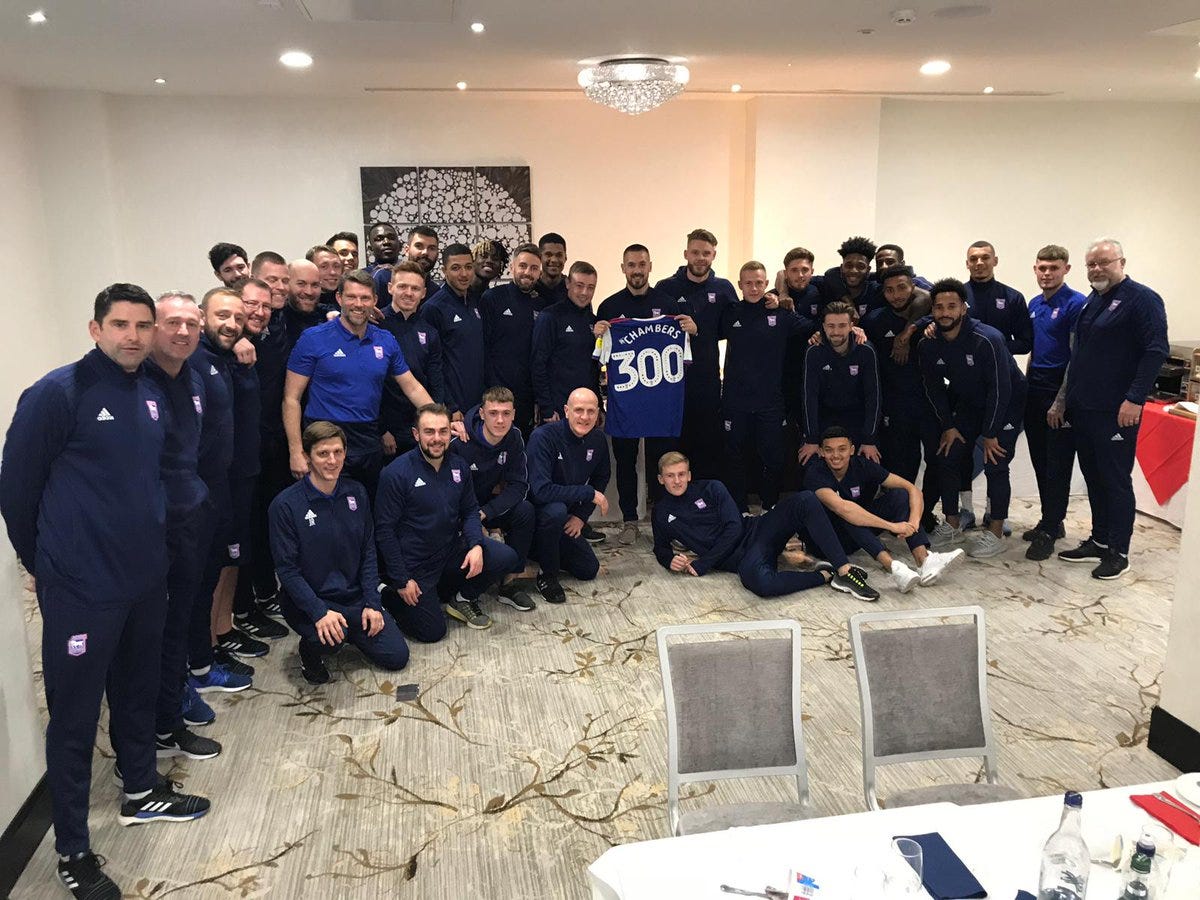 Squad and staff of Ipswich Town photographed in a conference room, celebrating Luke Chambers' 300th appearance for the club