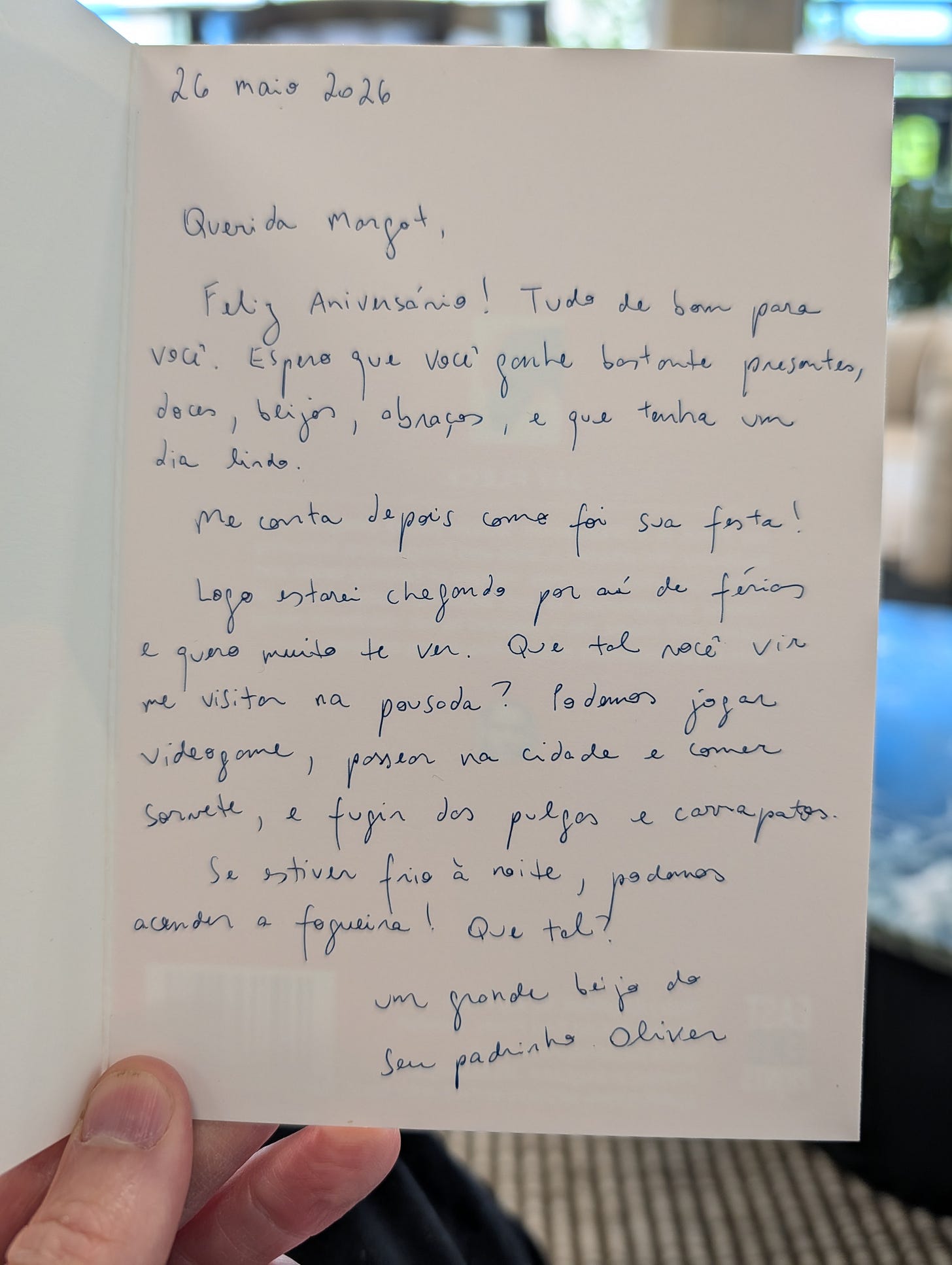 Handwritten letter on cream paper dated 26 maio 2026, beginning "Querida Margot" in Portuguese. The letter is written in blue ink in an informal, flowing hand and discusses birthday wishes and plans to visit the guesthouse.