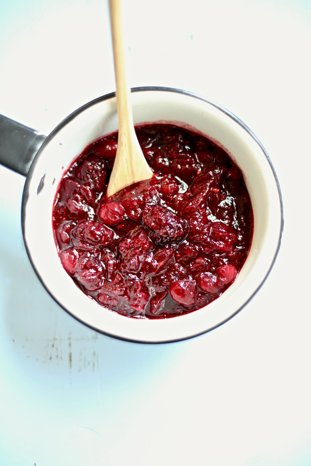 cranberry sauce in a white saucepan with a wodden spoon coming out the top side. cranberry sauce in a white saucepan with a wodden spoon coming out the top side.