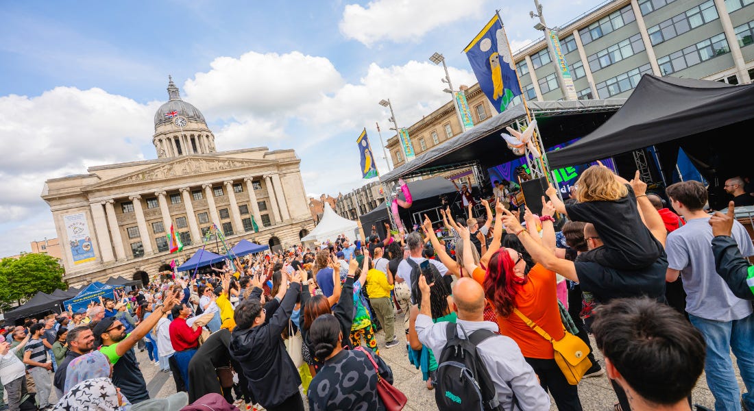 A crowd of people in Nottingham's Old Market Square with their hands raised A crowd of people in Nottingham's Old Market Square with their hands raised