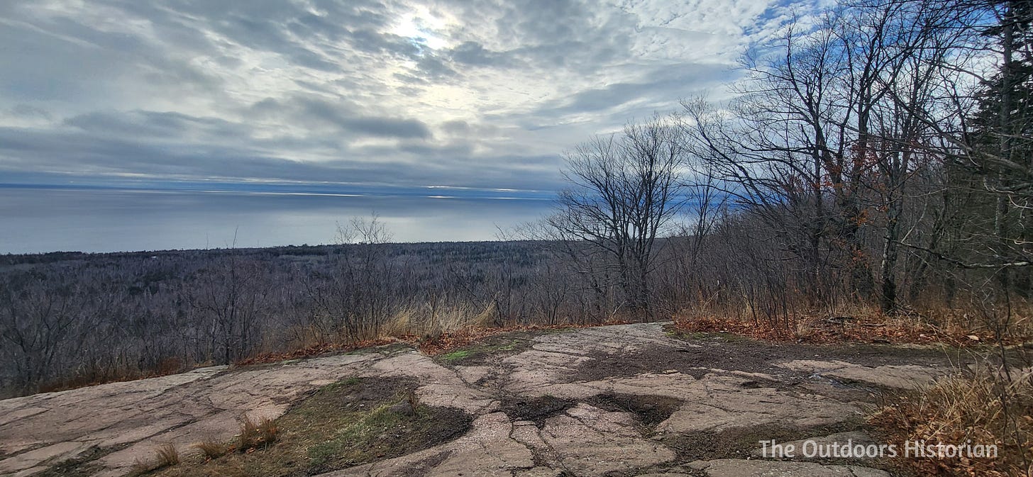 An image of a rocky overlook high above trees and a lakeshore.