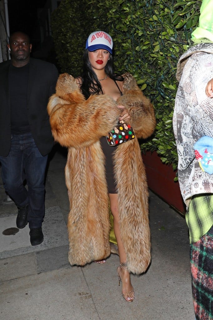 Rihanna wearing a fur coat and baseball cap.