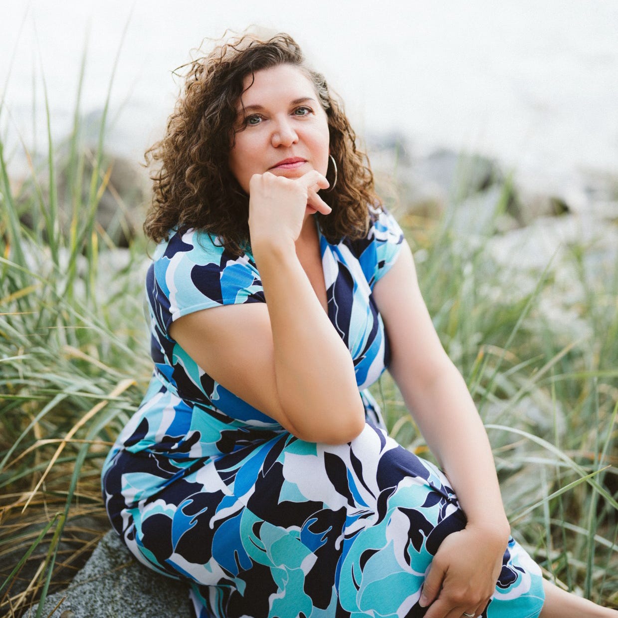 A photo of Amy S. Kaufman on a beach scene, sitting on gorse grass wearing a blue and white dress A photo of Amy S. Kaufman on a beach scene, sitting on gorse grass wearing a blue and white dress
