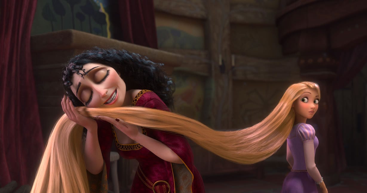 Mother Gothel holds Rapunzel's hair up to her face and caresses it. Rapunzel looks on uneasily.