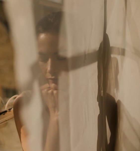 This may contain: a man standing in front of a curtain with his hand on his face and looking at the camera