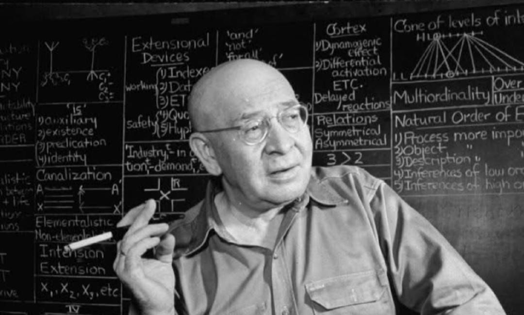 Some text visible on the blackboard behind Alfred Korzybski