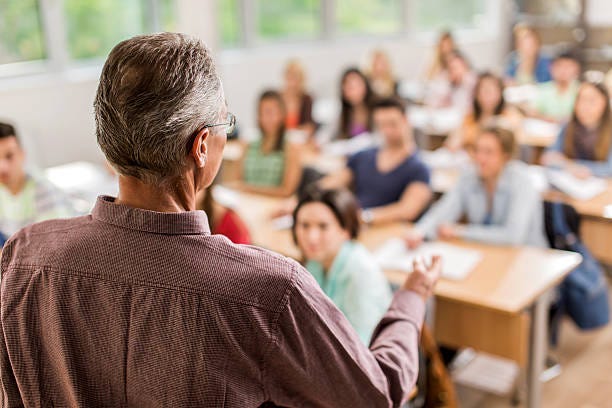 Rear view of teacher giving a lecture in the classroom.