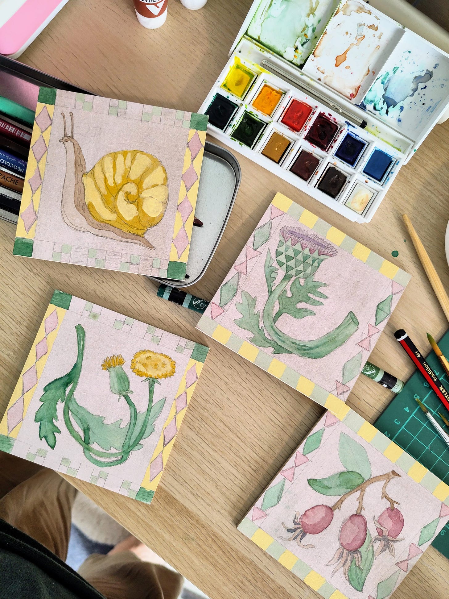 picture of 4 coasters painted with a snail, thistle, dandelion and some berries. picture of 4 coasters painted with a snail, thistle, dandelion and some berries.