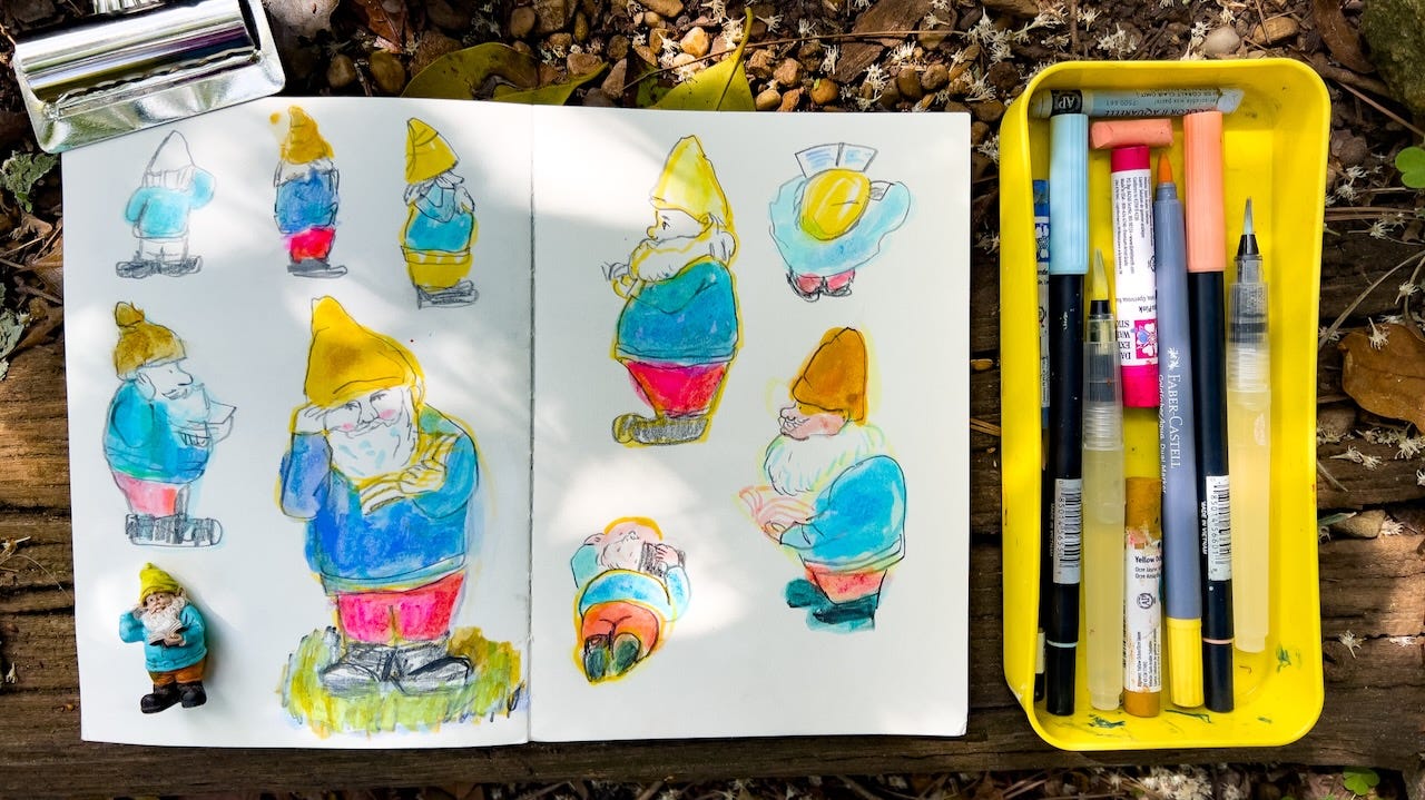 sketchbook lying on log with gnome illustrations and a figurine