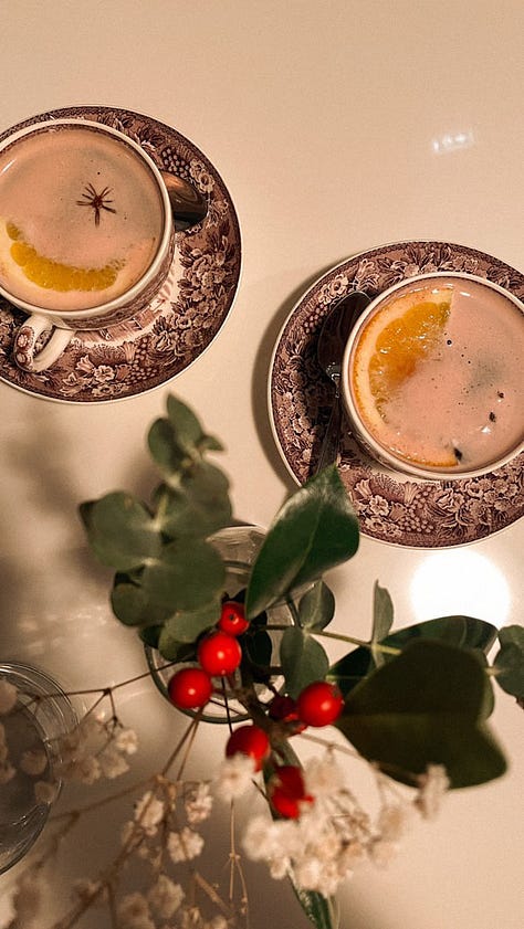 1) A sage green tea pot sitting next to it's lid on a black & white speckled counter. 2) Two dark purple and white china tea cups filled with tea & orange slices, sitting next to a sprig of holly berries. 3) A frog in a red & white mushroom outfit, resting atop a beige-coloured pumpkin. 4) Out a window, a golden sunrise across a city-scape. 5) A stack of six artistically decorated soda cans. 6) 5 old & differently shaped keys.