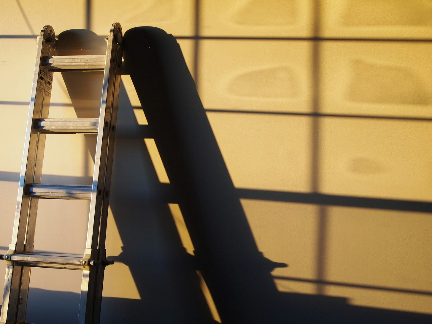 black metal ladder leaning on white wall black metal ladder leaning on white wall