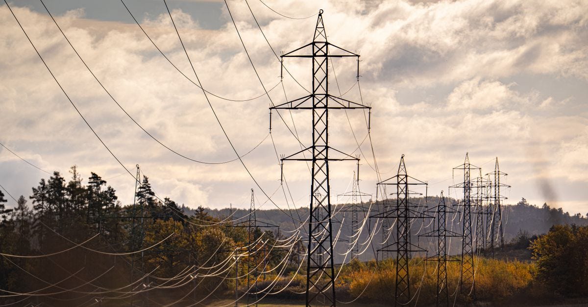Electric pylons stretch across a picturesque autumn landscape, under a dramatic sky.