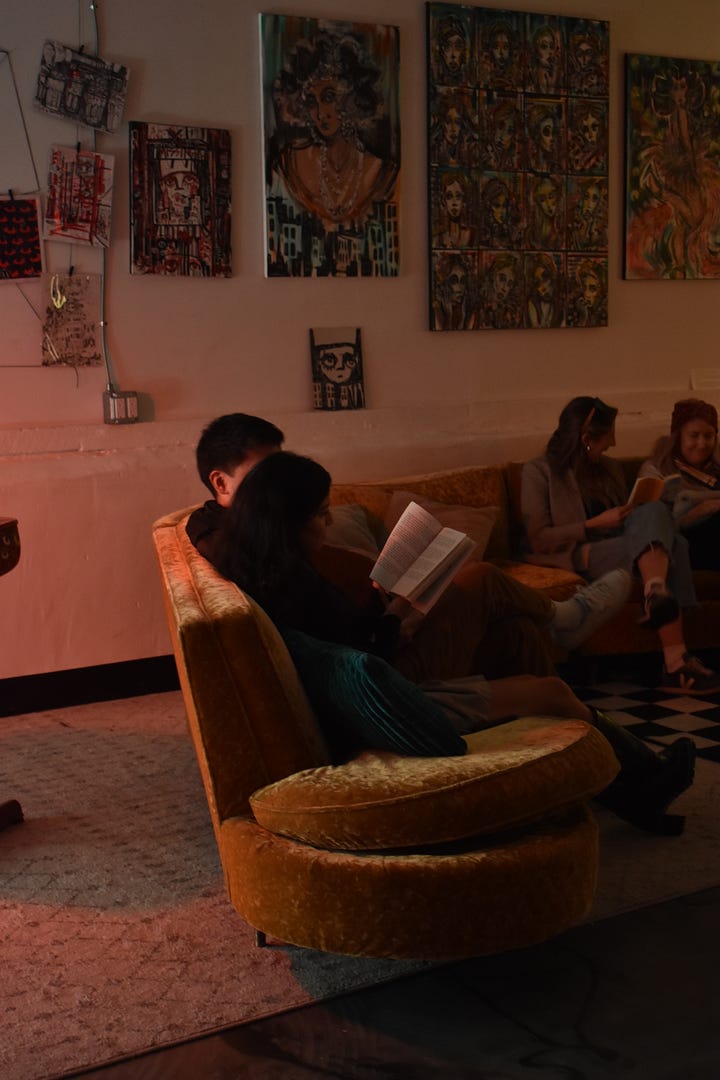 pictures of author signing book at book launch event, and aesthic placement of candles, dim light, and books displayed in accordion style