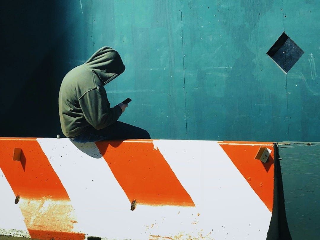 person in hooded jacket using smartphone