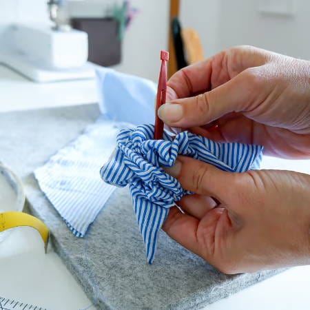 pushing out the corner of the fabric strip with a plastic stiletto pushing out the corner of the fabric strip with a plastic stiletto
