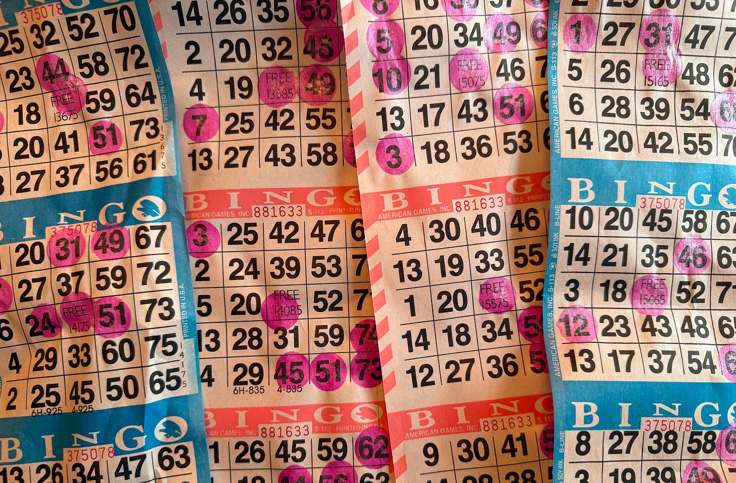 Newsprint bingo boards that have been marked up with purple dauber marks